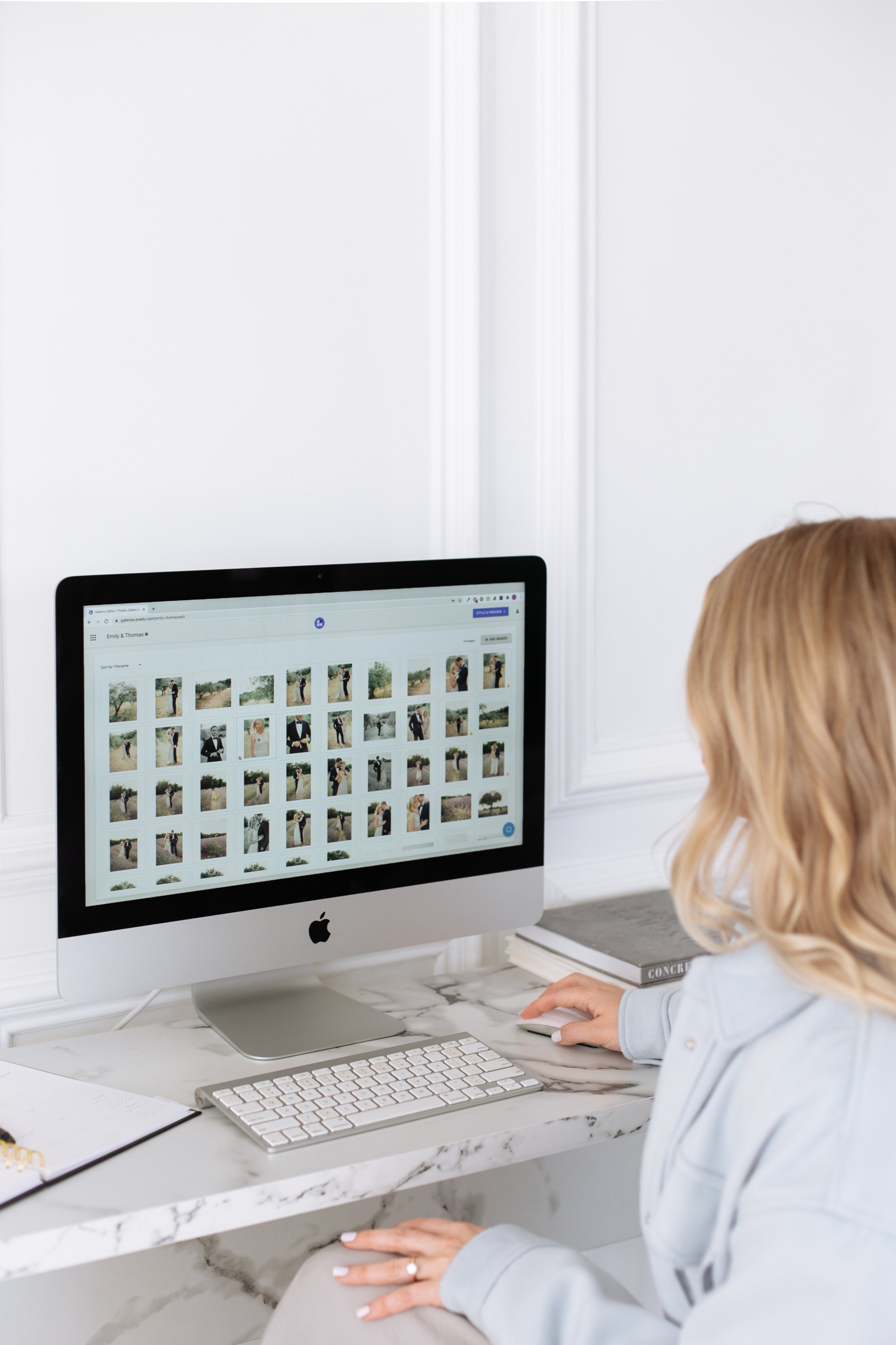 An over-the-head shot of a women looking at the screen of a iMac while scrolling 