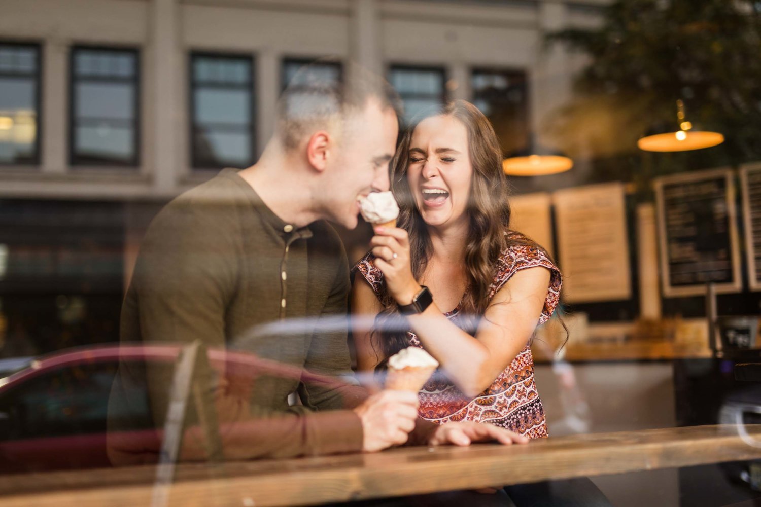 Shot of a couple through the window as they eat ice cream  