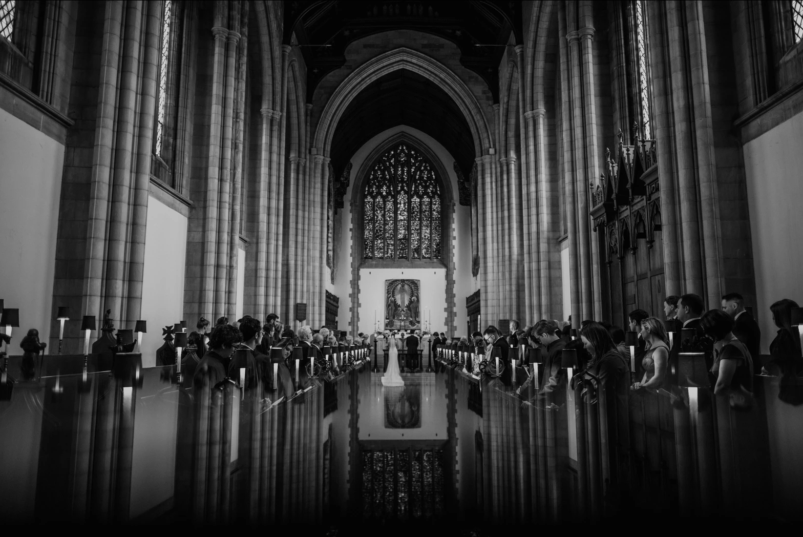 A black and white image of a bride and groom standing at the altar of the wedding ceremony