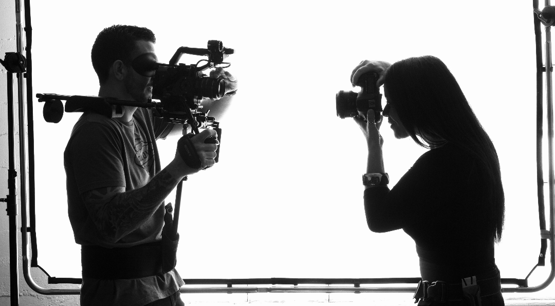 A silhouette of two photographers pointing cameras at each other
