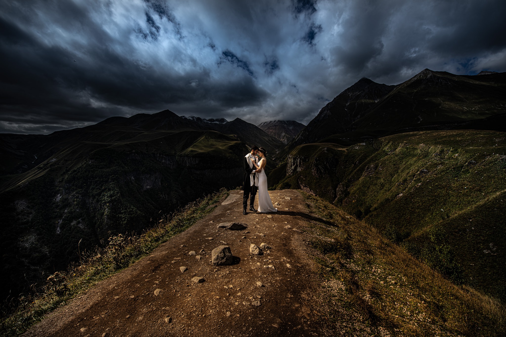 A bride and groom posing at a mountain top