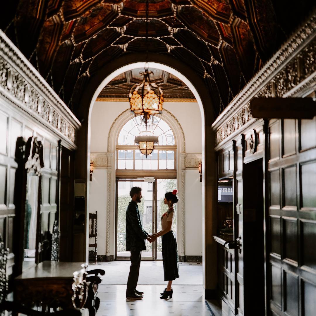 A couple posing under a doorway while holding hands