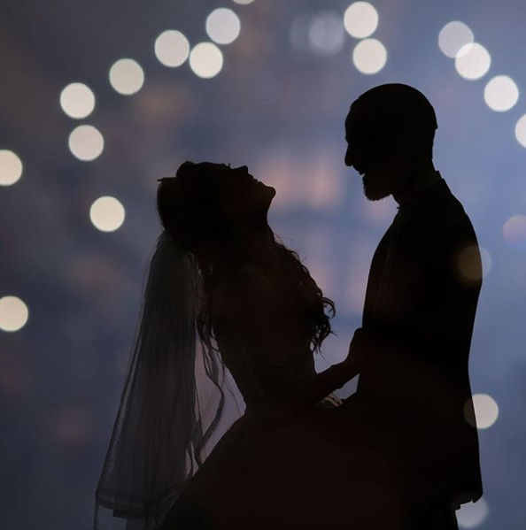 A silhouette of a bride and groom posing with a bokeh background