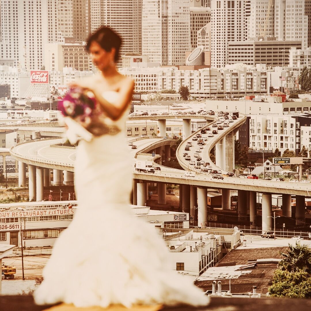 A bride posing on a high vantage point in front of a cityscape