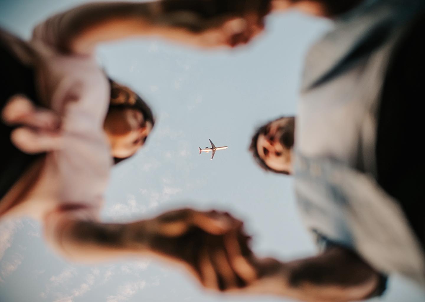 A worm's eye view of a couple holding hands and an airplane flying 