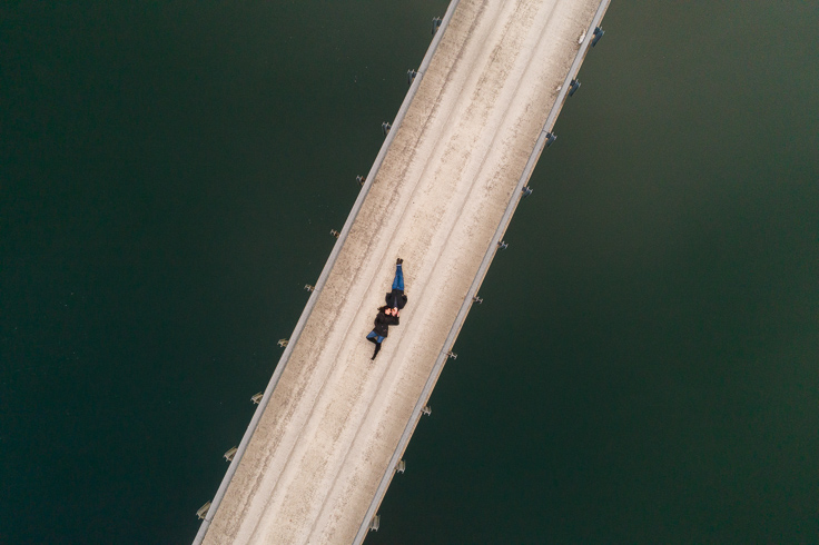 A bird's eye view of a couple lying down on a bridge