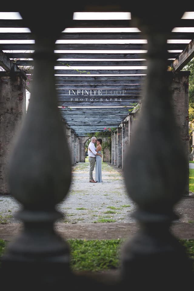 A shot of a couple holding each other taken through the frame of a railing 