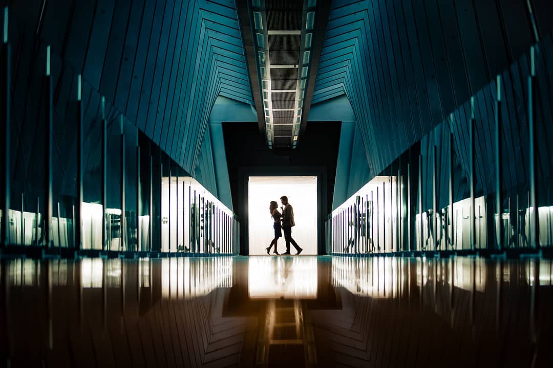 A silhouette of a couple looking at each other standing under a doorway 