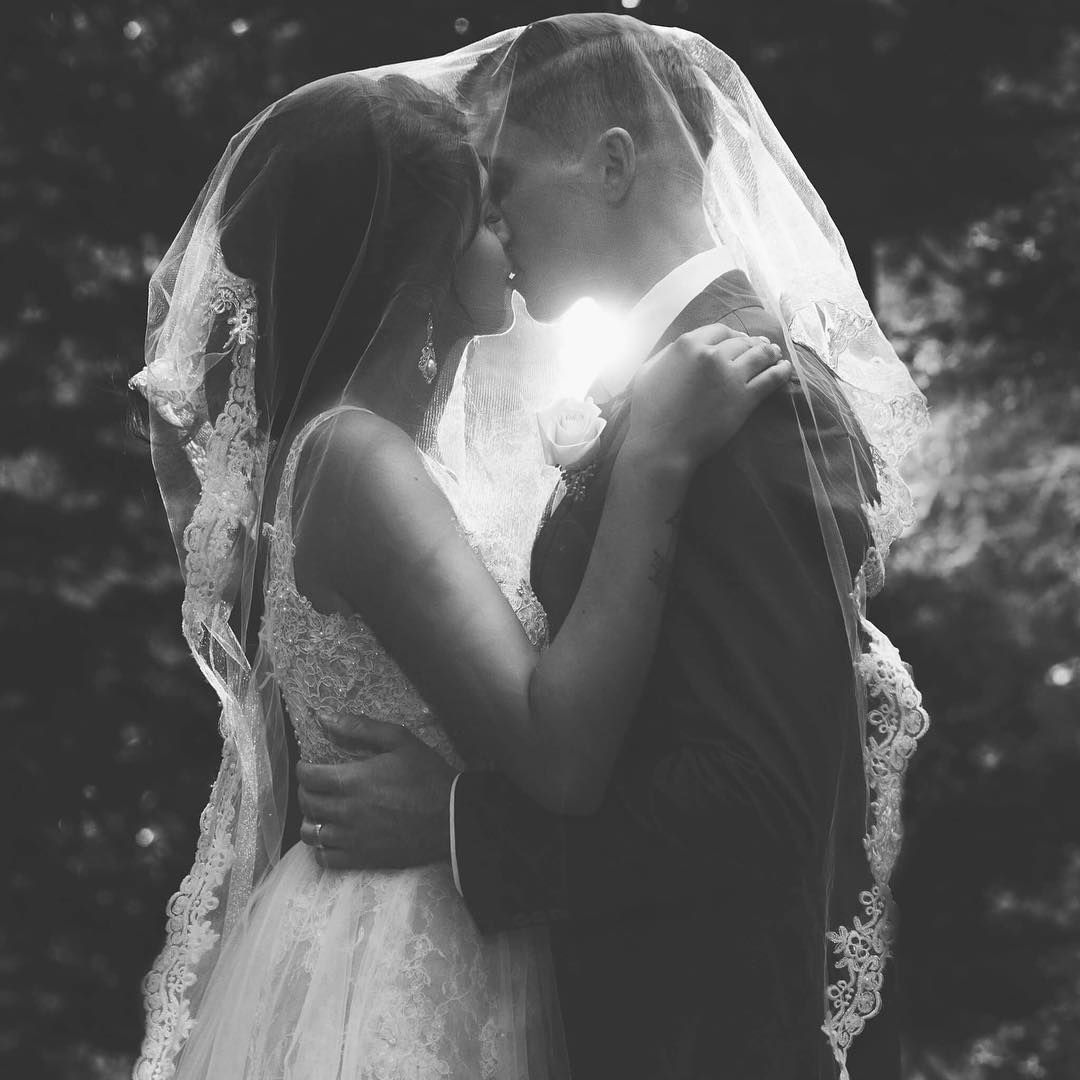 An under veil shot of a bride and groom kissing