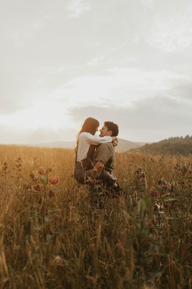 A couple posing in the middle of a field while holding each other