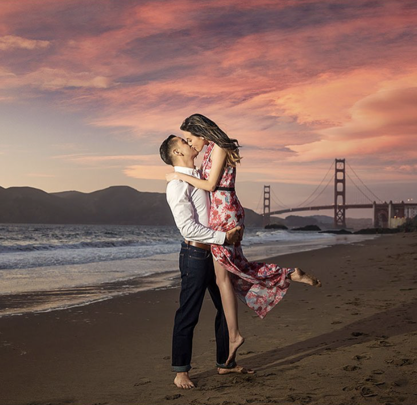 A couple posing for a kiss by the beach during sunset