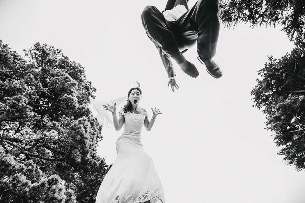 A black and white jump shot of a bride and groom