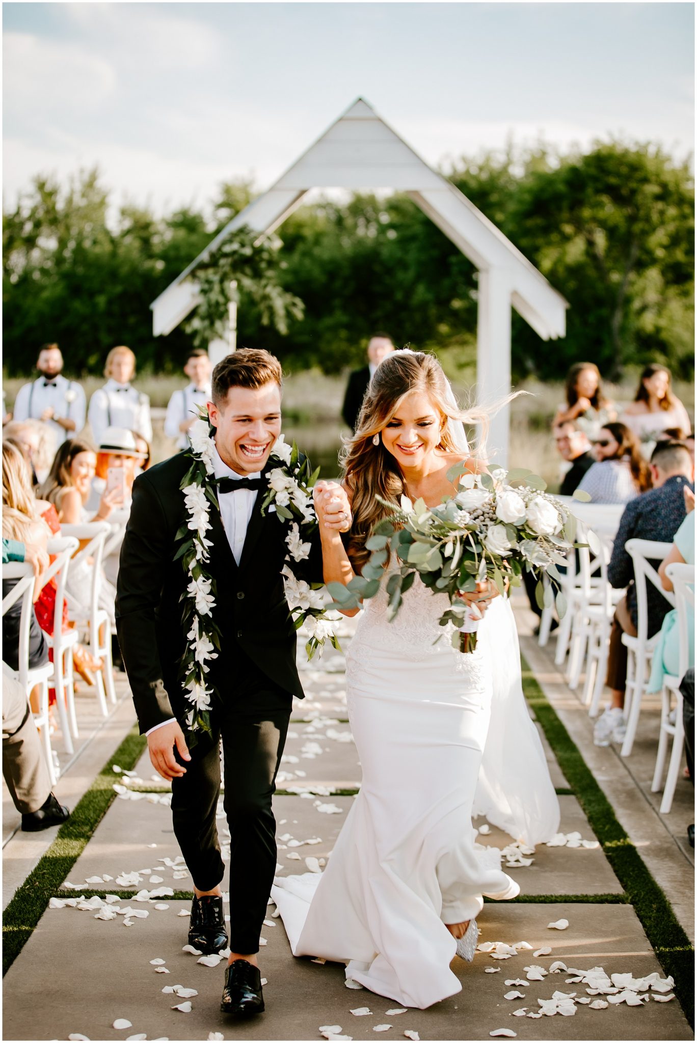 A bride and groom walking down the aisle while holding hands 