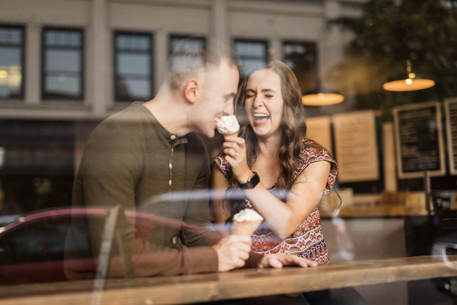 a couple laughing while the bride feeds an ice cream cone to the groom