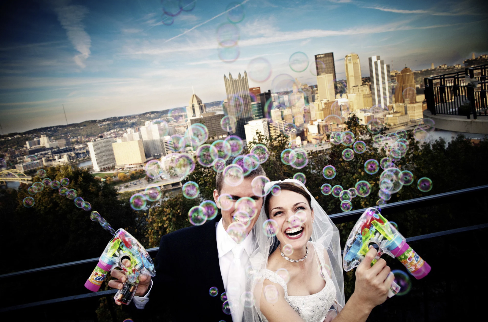 a recently married couple laughing and playing with bubble shooters