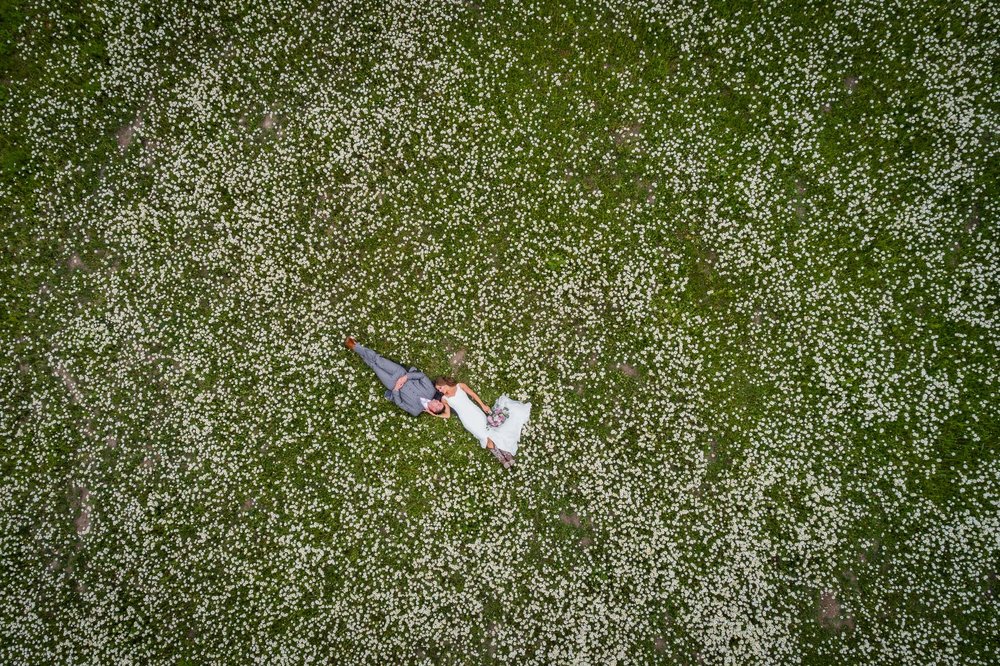 An aerial view of a bride and groom posing in a field  