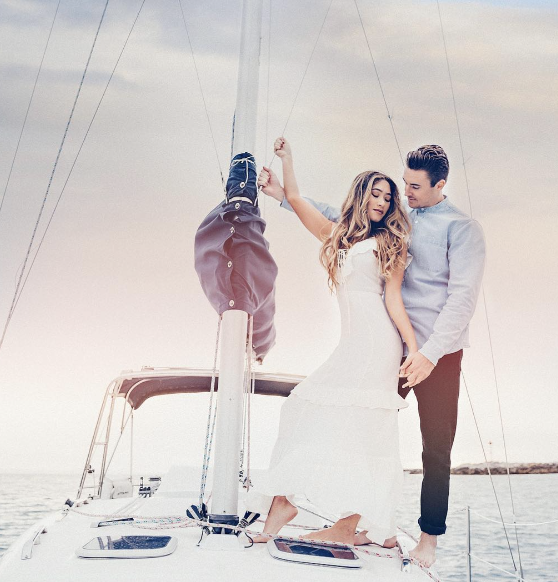 a couple holding hands while standing on an yacht