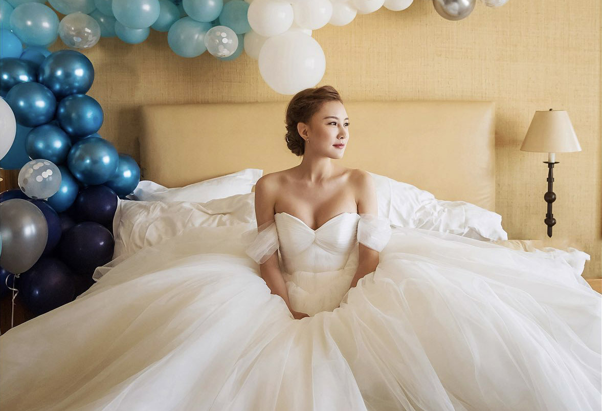 a bride in wedding dress sitting on a sofa surrounded by balloons
